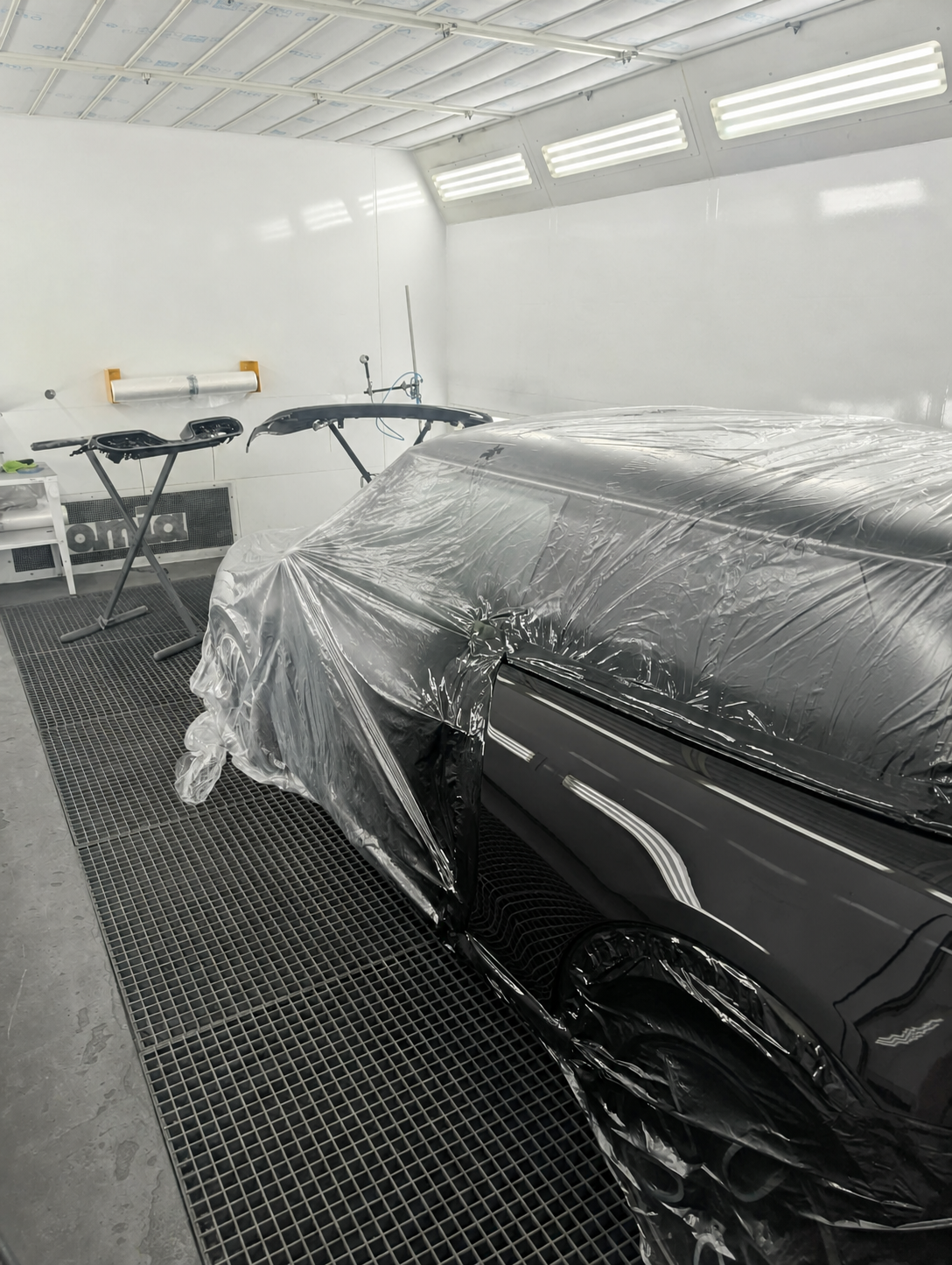 Véhicule noir soigneusement protégé en cabine de peinture